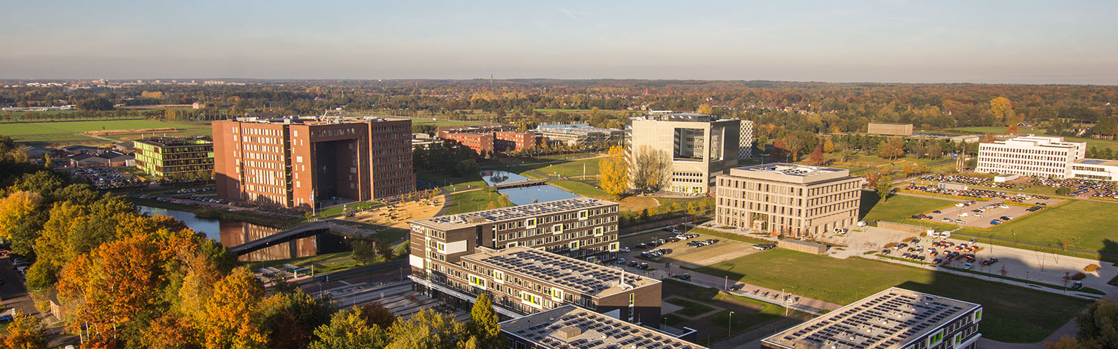 An aerial view of several modern school buildings with a river running through the middle of the campus.